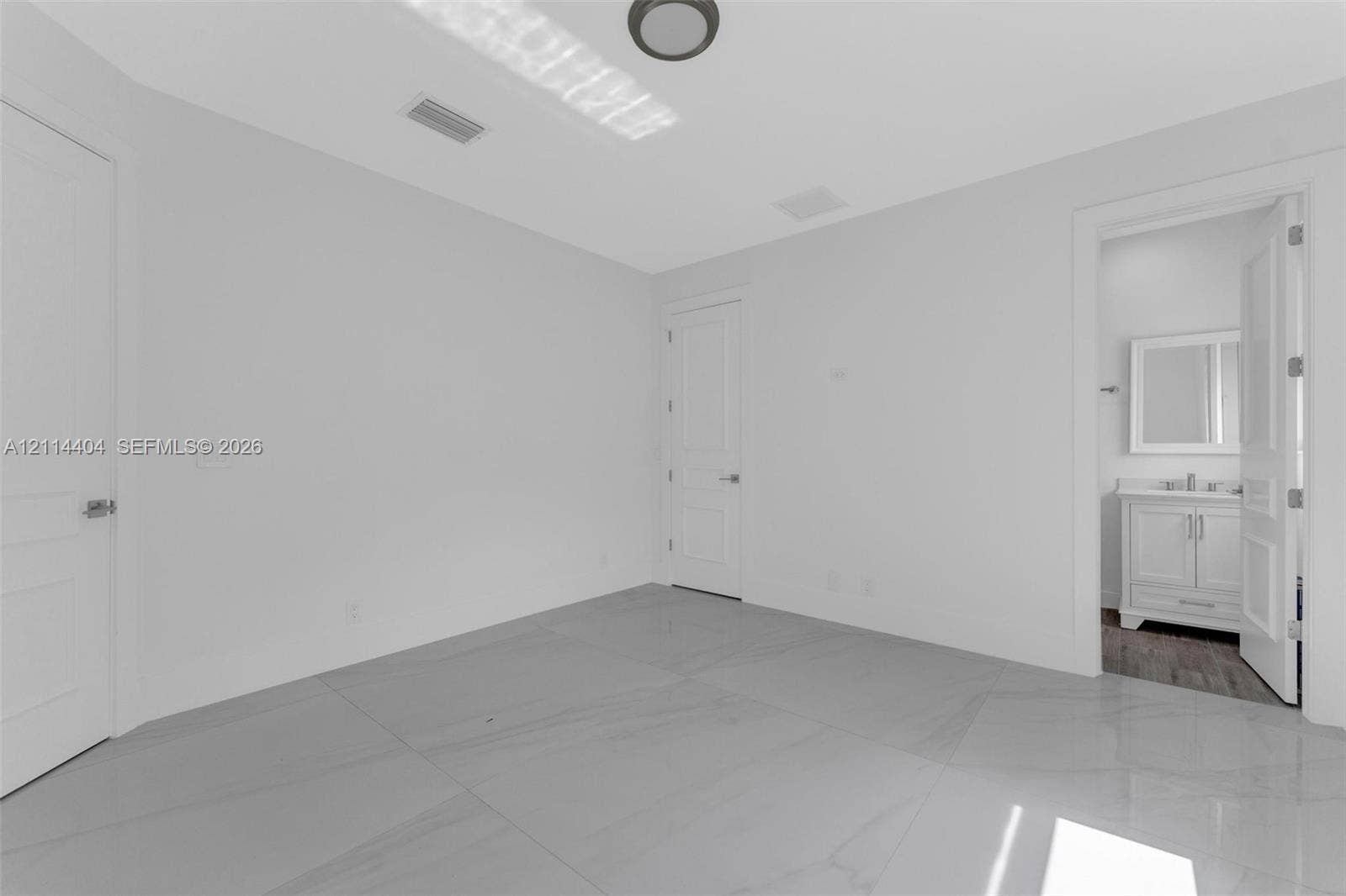 Room featuring large-format tile flooring, smooth ceilings with flush-mount lighting, and solid-core panel doors
