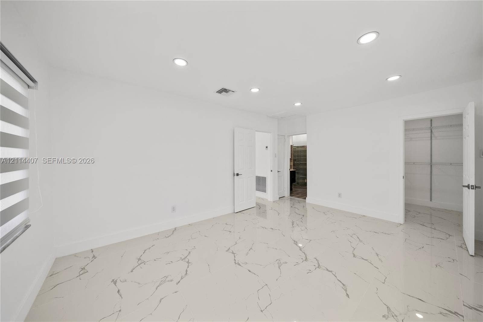Neutral-toned flooring with veined detailing, recessed ceiling lighting, and built-in closet storage