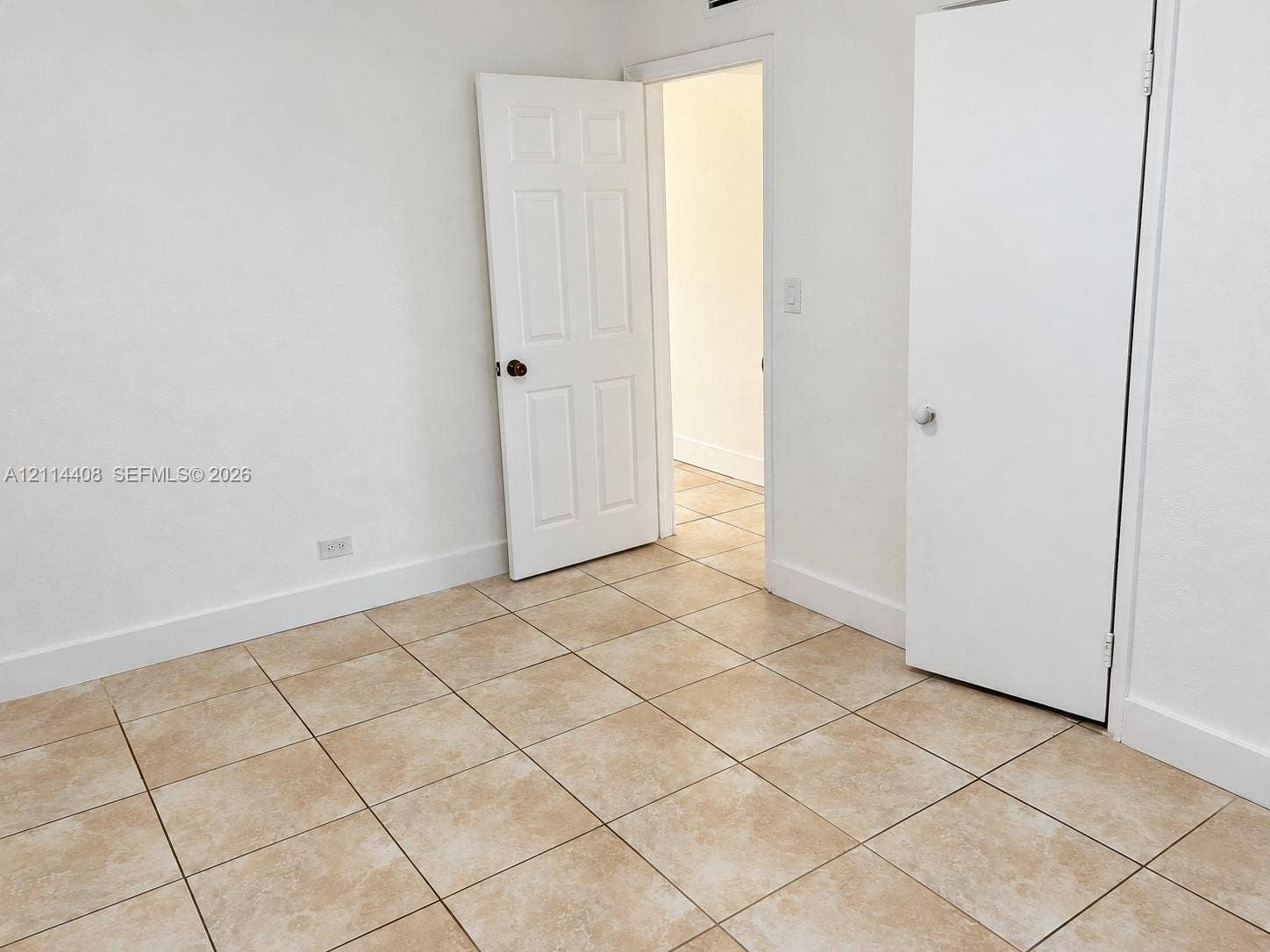 Interior space featuring neutral tile flooring, six-panel interior doors, and a built-in closet with a swing-style door