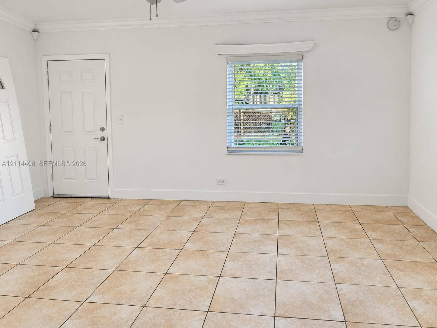 Neutral-toned ceramic tile flooring, multi-panel entry door, and a single-hung window with horizontal blinds