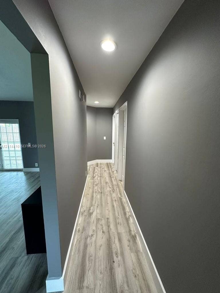 Hallway featuring wood-finish flooring, neutral-toned walls, and recessed ceiling lighting