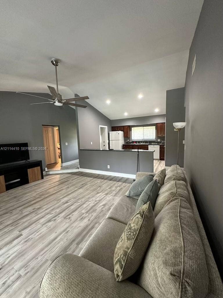 Vaulted ceilings, wood-finish flooring, recessed lighting, ceiling fan, and peninsula kitchen layout