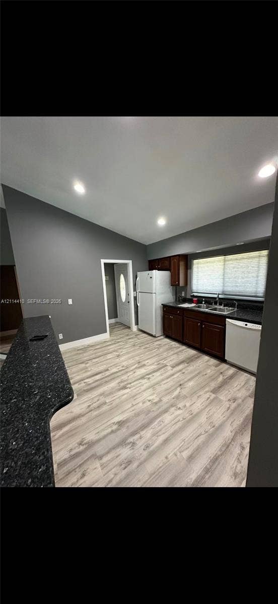 Kitchen featuring dark-toned cabinetry, solid surface countertops, a breakfast bar, wood-finish flooring, and recessed lighting