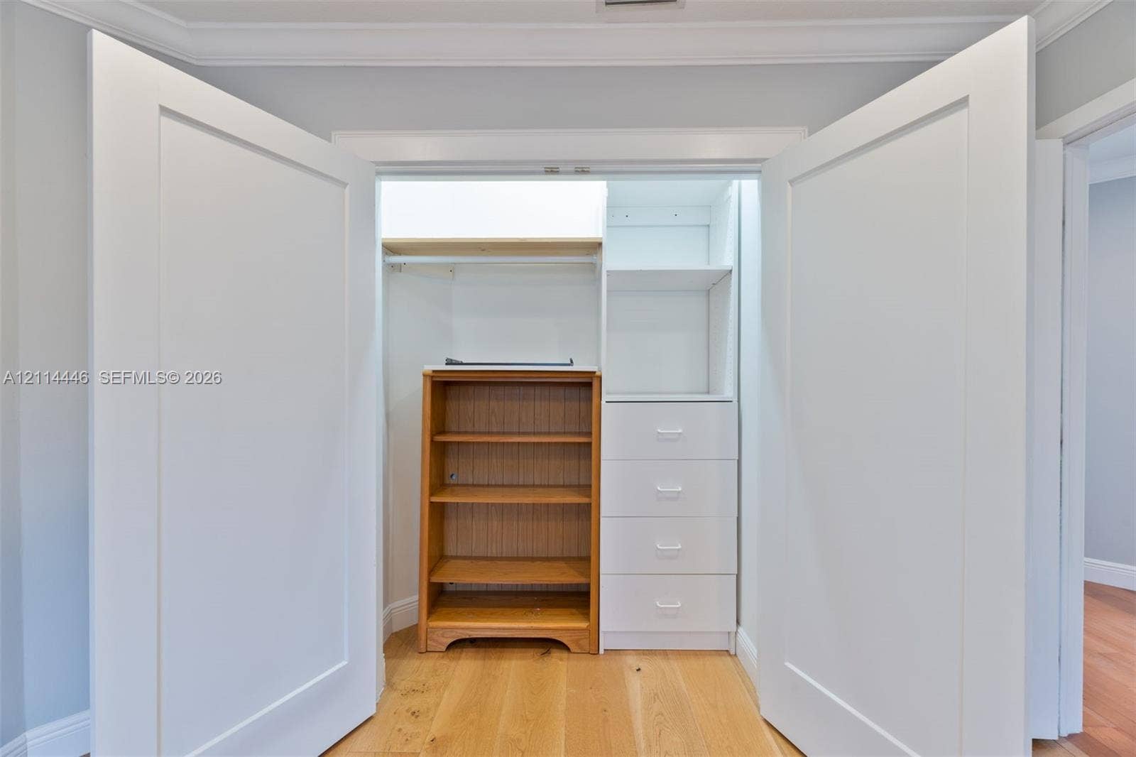 Reach-in closet featuring double shaker-style doors, integrated white cabinetry, four built-in drawers, and overhead shelving