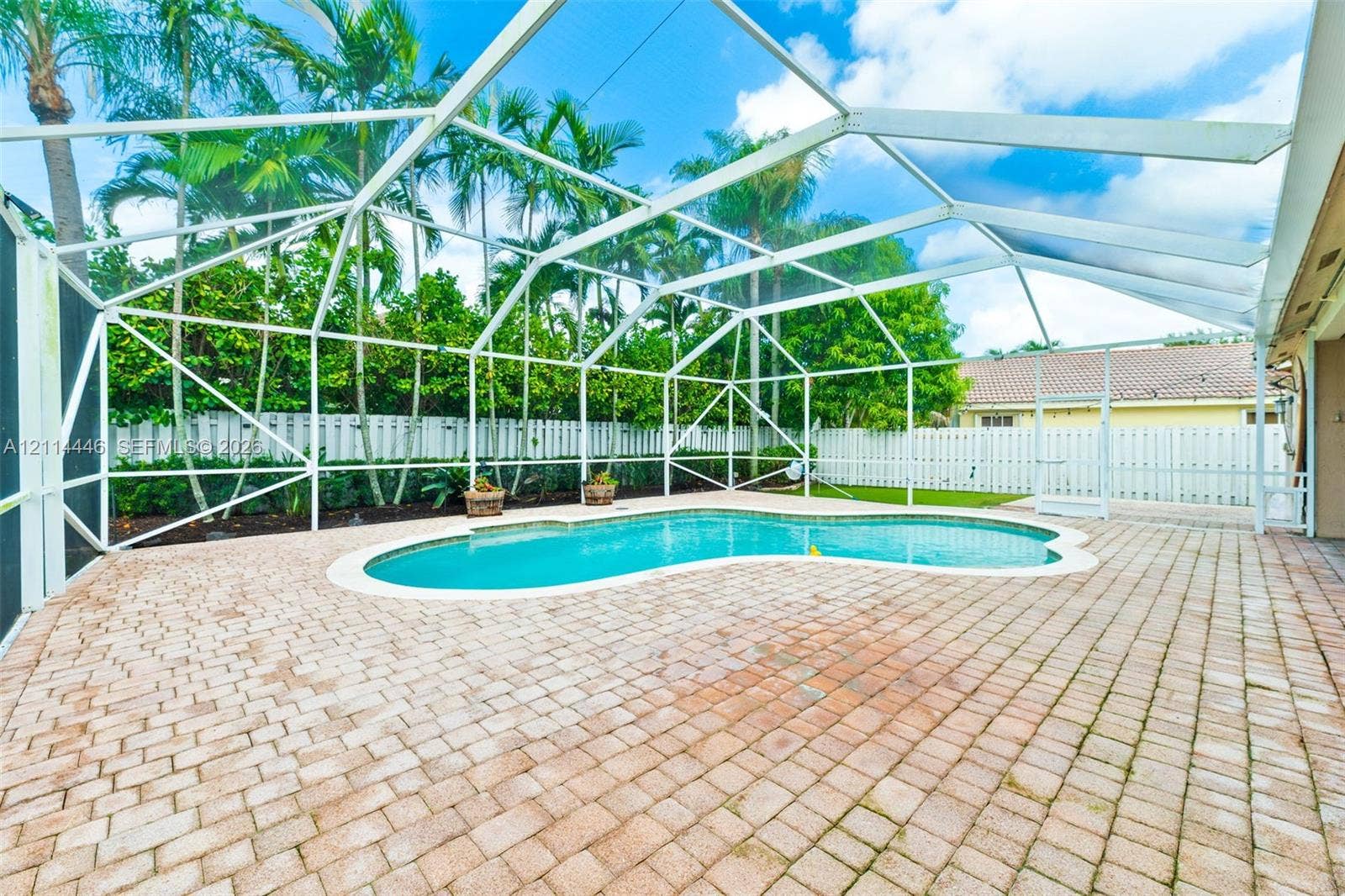 Screened-in pool area featuring a paver patio and perimeter privacy fencing