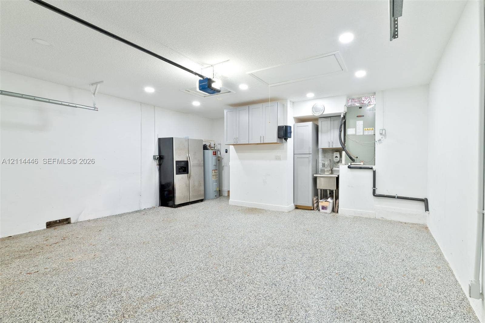 Garage space featuring an epoxy-coated floor, recessed lighting, built-in storage cabinetry, and a dedicated utility sink area