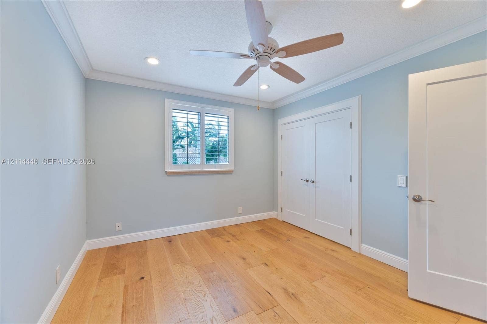 Room featuring wood-finish flooring, crown molding, double-door closet, recessed lighting, and plantation shutters