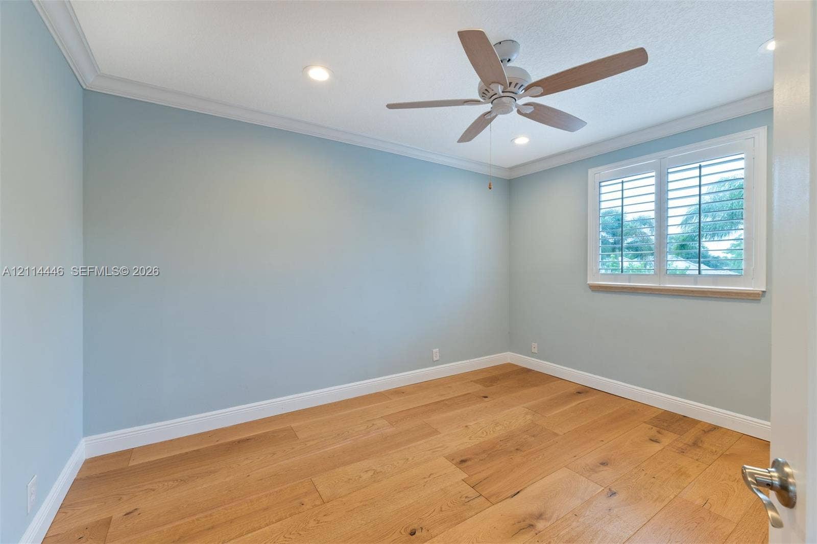 Interior room featuring wood-finish flooring, recessed lighting, crown molding, a ceiling fan, and a window fitted with plantation shutters