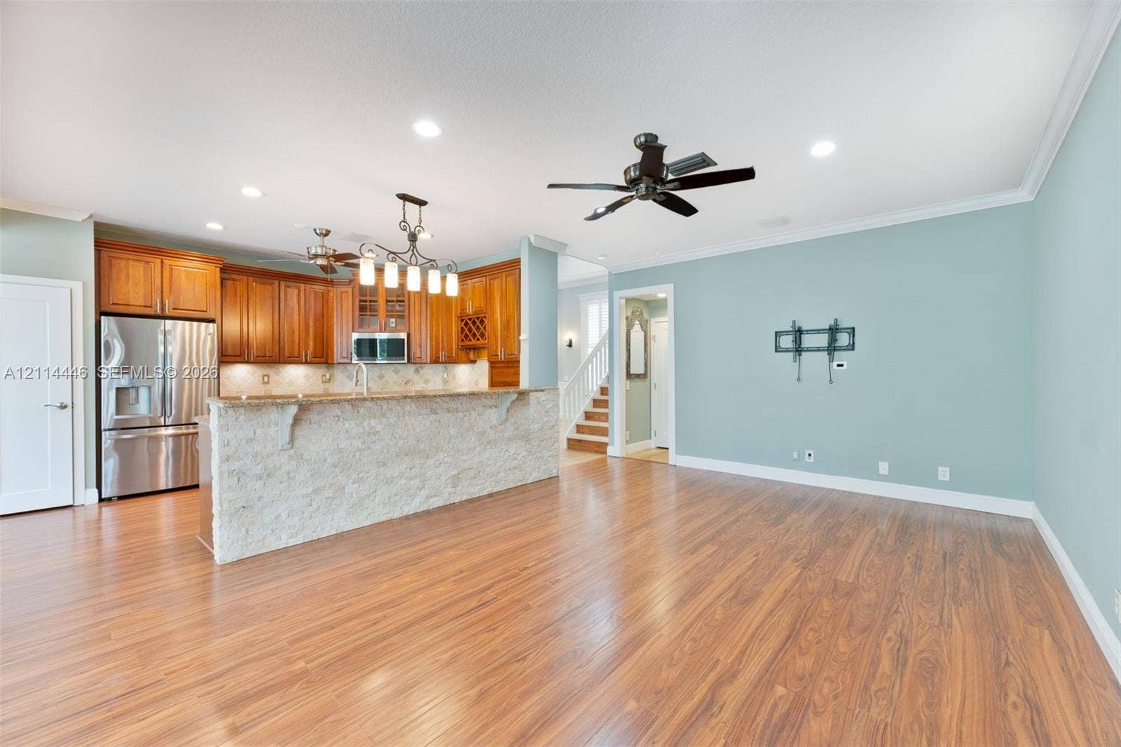 Kitchen featuring wood cabinetry, stone-finish countertops, textured stone-veneer breakfast bar, wood-finish flooring, and recessed ceiling lighting