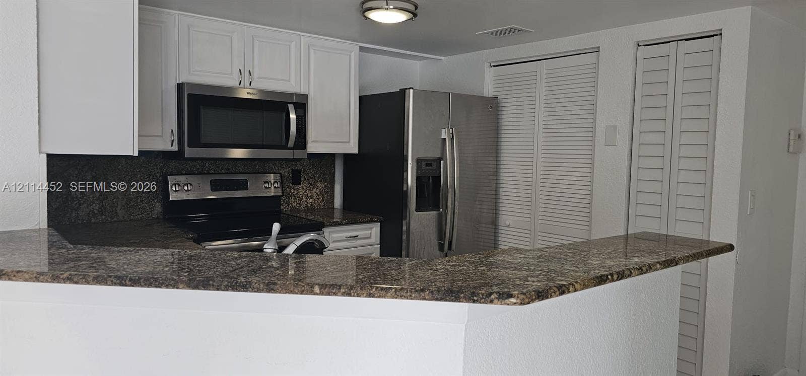 9044 W Atlantic Boulevard, #314, Coral Springs, Coral Springs, FL 33071 Kitchen featuring white cabinetry, stone countertops, stainless steel appliances, and louvered-style closet doors