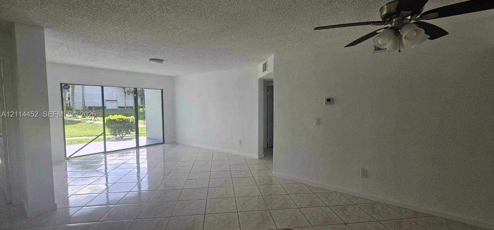 9044 W Atlantic Boulevard, #314, Coral Springs, Coral Springs, FL 33071 Large living space featuring tile flooring, ceiling fan with light fixture, and floor-to-ceiling sliding glass doors