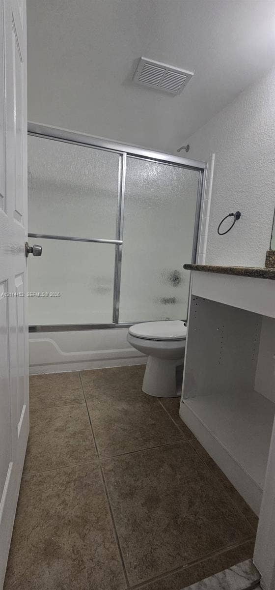 9044 W Atlantic Boulevard, #314, Coral Springs, Coral Springs, FL 33071 Bathroom featuring tile flooring, a white vanity with a stone-surface countertop, and a shower-tub combination enclosed by sliding glass doors