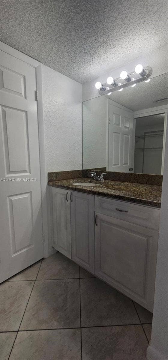 9044 W Atlantic Boulevard, #314, Coral Springs, Coral Springs, FL 33071 Vanity featuring a stone countertop with an integrated basin, white cabinetry, a large wall-mounted mirror, and tile flooring