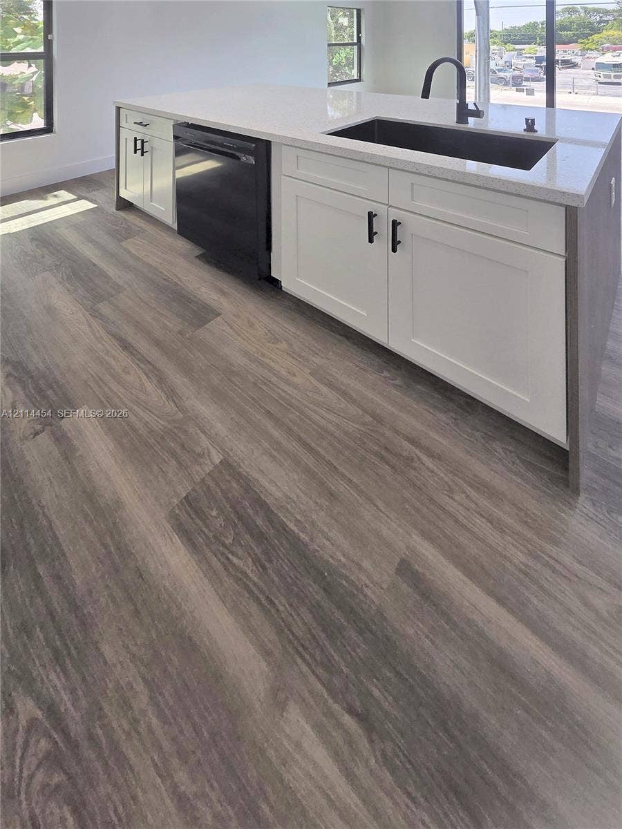 401 Pembroke Road, #203, Hallandale Beach, Hallandale Beach, FL 33009 Kitchen island featuring white shaker-style cabinetry, matte black hardware, stone-composite countertop, undermount sink, and wood-finish flooring