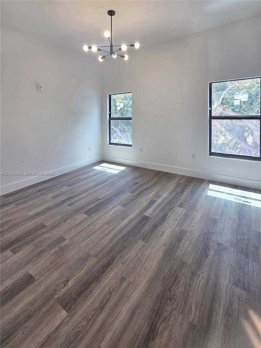 401 Pembroke Road, #203, Hallandale Beach, Hallandale Beach, FL 33009 Interior space featuring wood-finish flooring, high ceilings, large windows with dark frames, and a multi-arm modern chandelier
