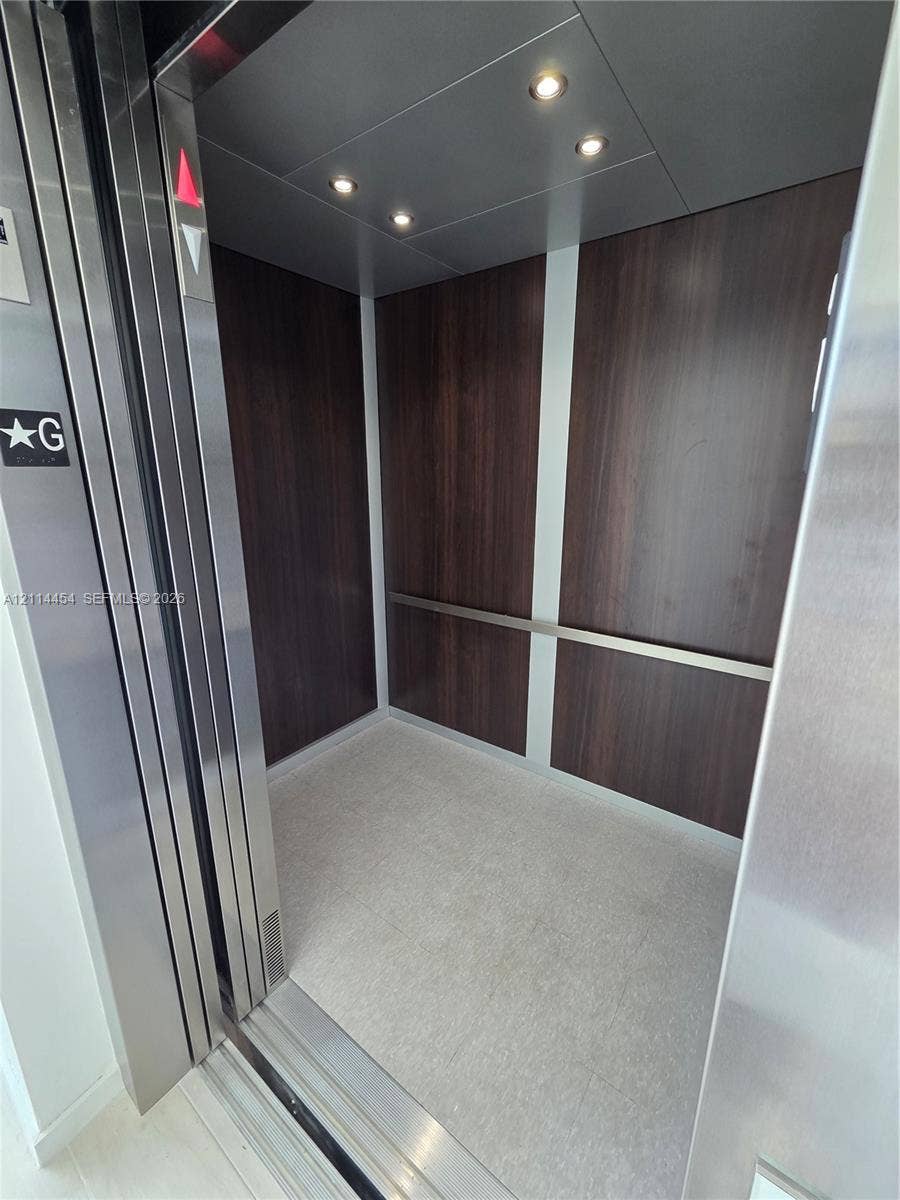 401 Pembroke Road, #203, Hallandale Beach, Hallandale Beach, FL 33009 Private elevator featuring stainless steel door frames, rich wood-finish wall paneling, integrated recessed ceiling lighting, and a horizontal metal handrail
