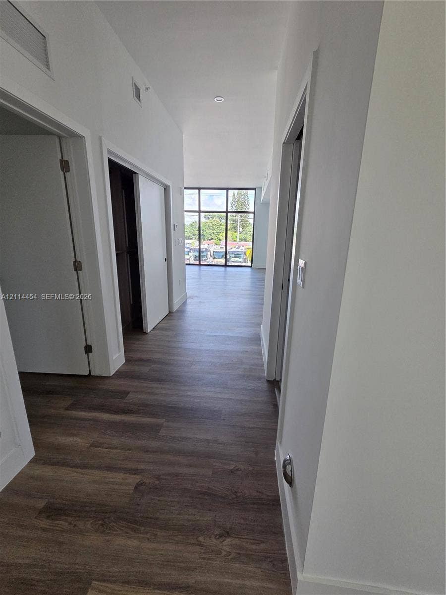 401 Pembroke Road, #203, Hallandale Beach, Hallandale Beach, FL 33009 Hallway featuring wood-finish flooring, white walls, and floor-to-ceiling windows with dark framing