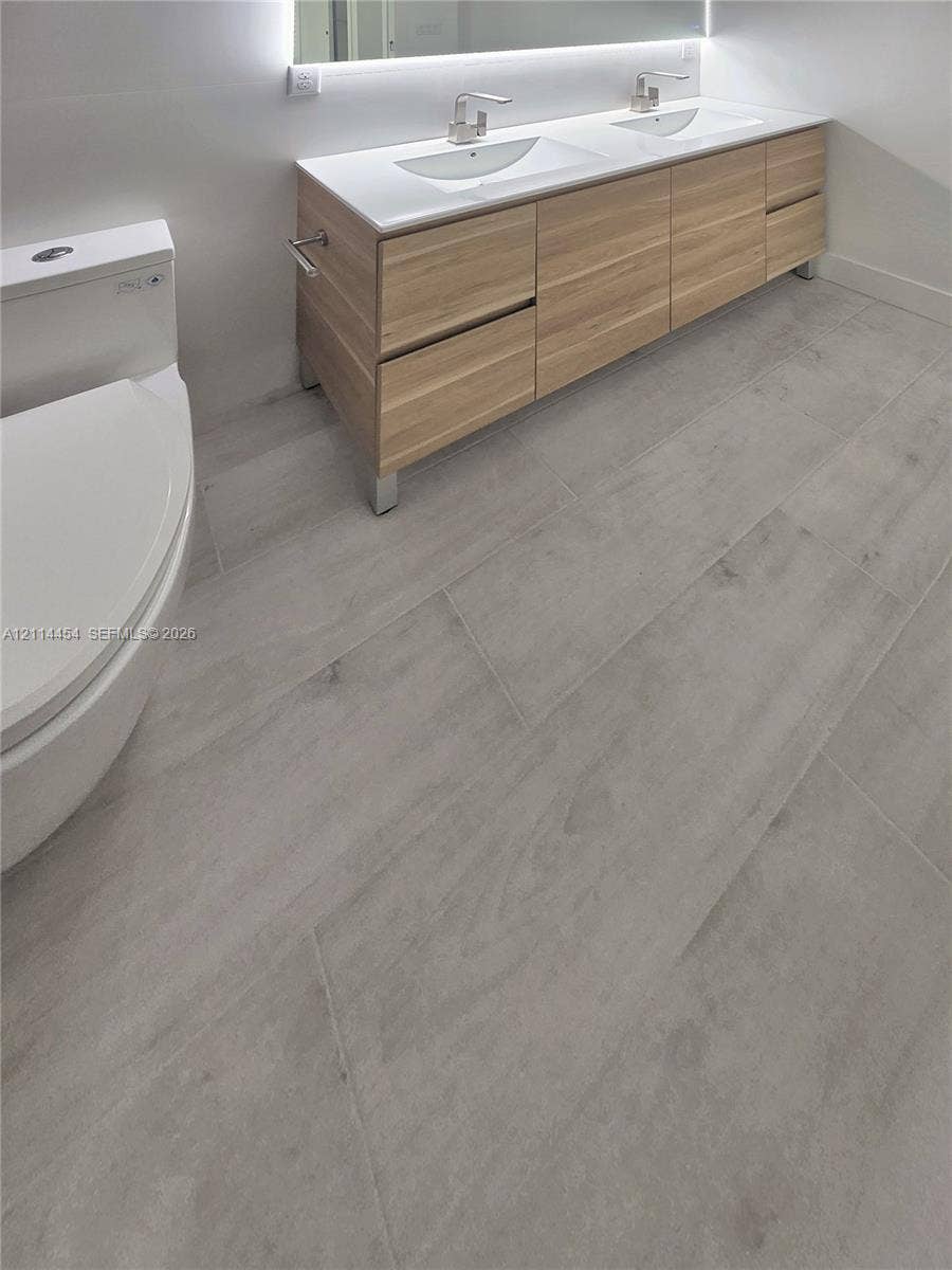 401 Pembroke Road, #203, Hallandale Beach, Hallandale Beach, FL 33009 Modern floating vanity featuring light-toned cabinetry, dual rectangular under-mount sinks, integrated lighting, and neutral large-format tile flooring