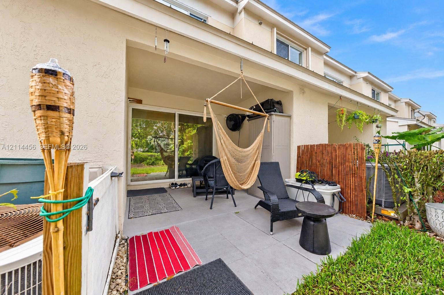 Covered concrete patio featuring large-format tile flooring and sliding glass door access