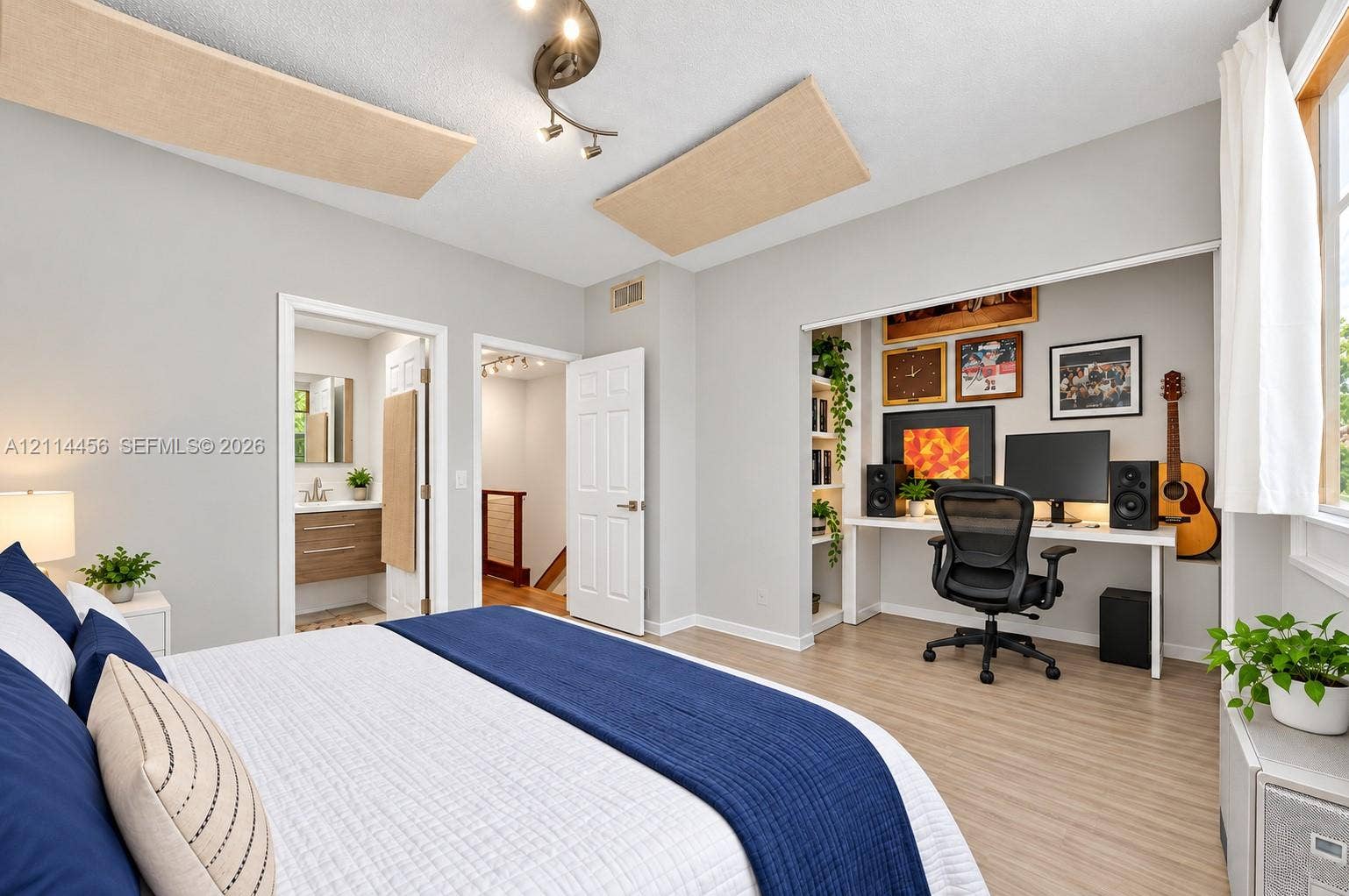 Room featuring wood-finish flooring, recessed built-in shelving, a dedicated work alcove, and a multi-directional ceiling light fixture