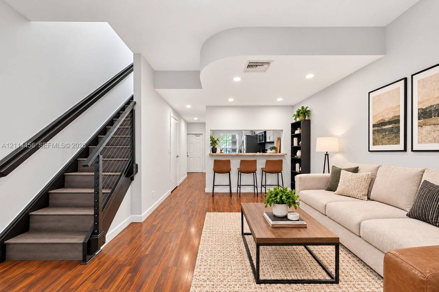 Interior space featuring wood-finish flooring, recessed lighting, and a staircase with matte black railings and cable balusters