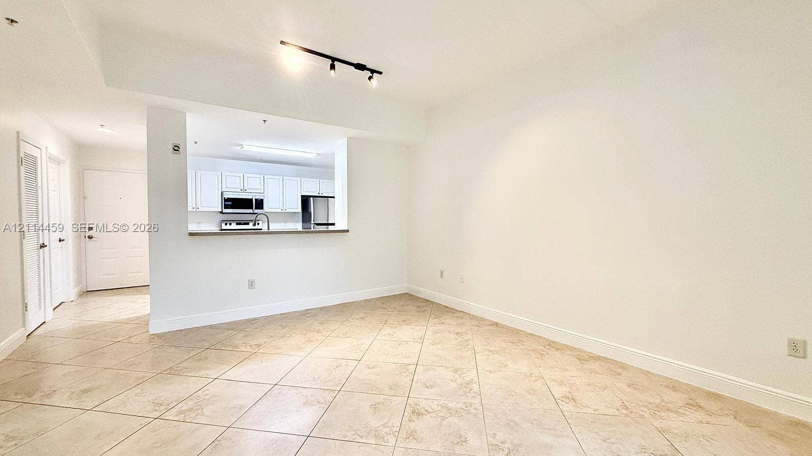 1203 Town Center Drive, #207, Jupiter, Jupiter, FL 33458 Open-concept interior featuring large-format ceramic tile flooring, neutral wall finishes, track lighting, and a breakfast bar pass-through to the kitchen area