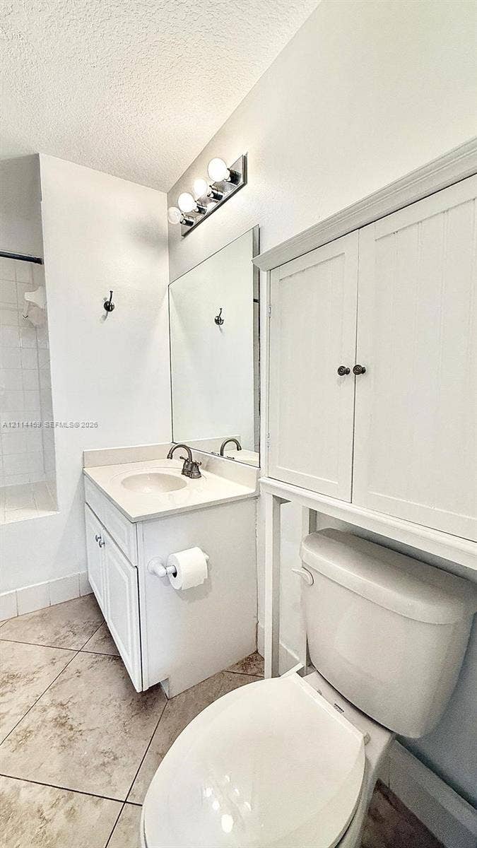 1203 Town Center Drive, #207, Jupiter, Jupiter, FL 33458 Bathroom featuring a white vanity with a neutral solid-surface countertop, an integrated sink, built-in over-toilet cabinetry, a large wall mirror, and tile flooring