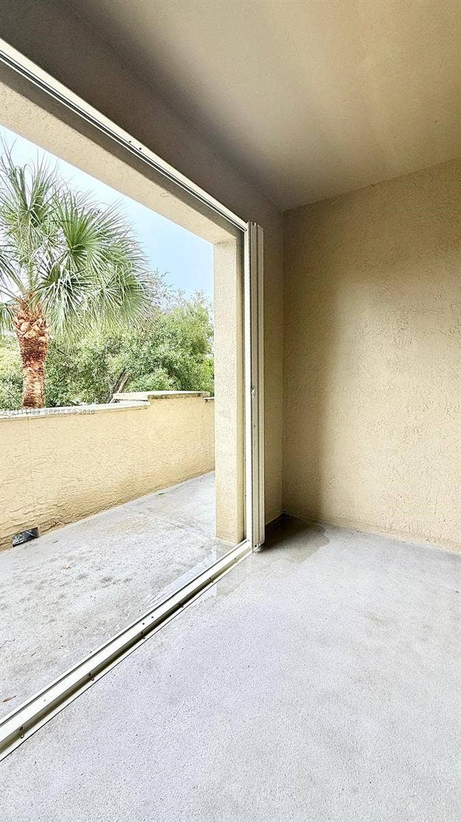 1203 Town Center Drive, #207, Jupiter, Jupiter, FL 33458 Covered balcony featuring concrete flooring, textured walls, and a glass-paneled sliding door