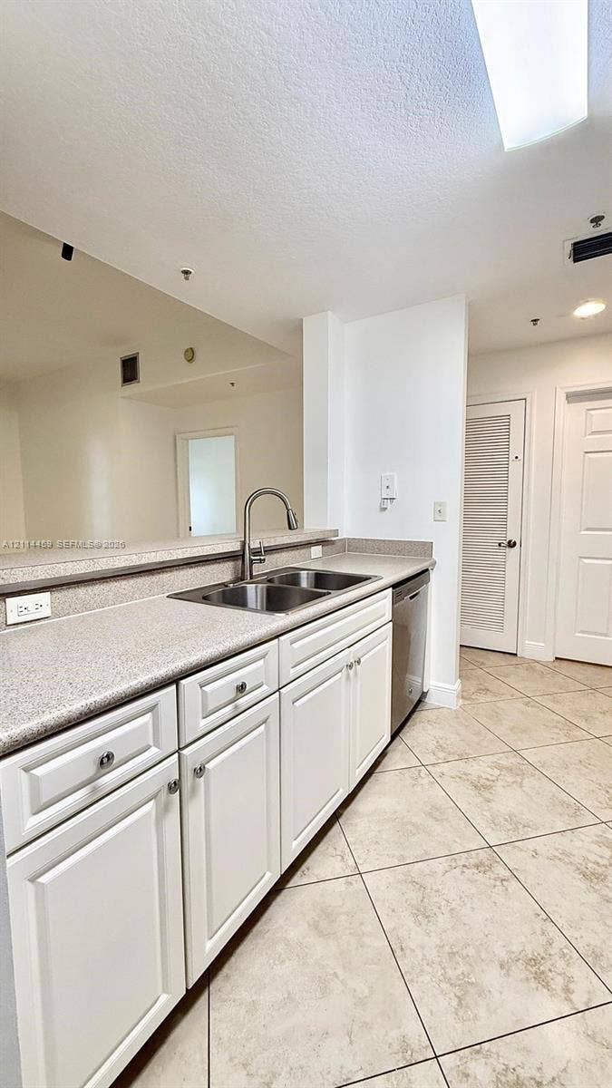 1203 Town Center Drive, #207, Jupiter, Jupiter, FL 33458 Kitchen featuring white shaker-style cabinetry, solid-surface countertops, dual-basin stainless steel sink with high-arc faucet, stainless steel dishwasher, and diagonal-set tile flooring