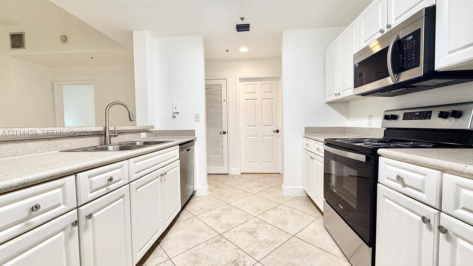 1203 Town Center Drive, #207, Jupiter, Jupiter, FL 33458 Kitchen featuring white cabinetry, stone-finish countertops, stainless steel appliances, a double-basin sink, and tile flooring