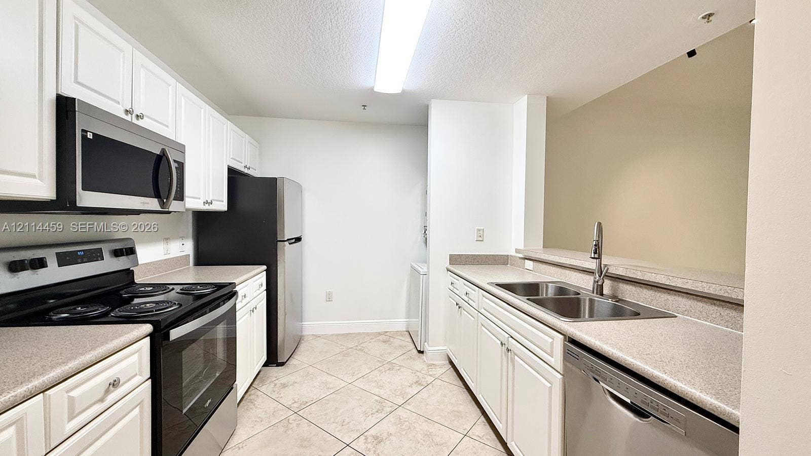 1203 Town Center Drive, #207, Jupiter, Jupiter, FL 33458 Kitchen featuring white cabinetry, solid surface countertops, a dual-basin stainless steel sink, tile flooring, and stainless steel appliances