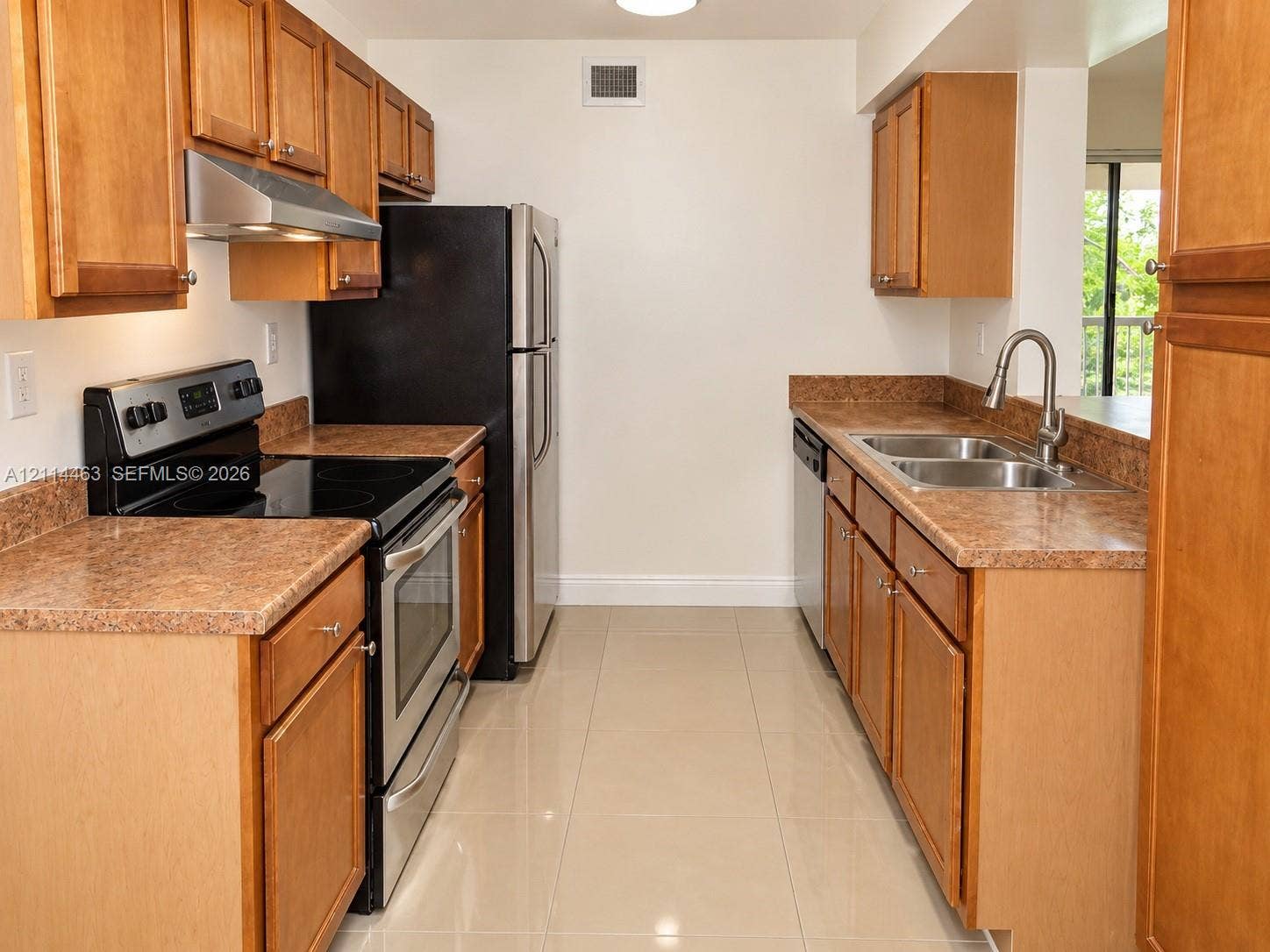 4970 NW 97th Place, #309, Doral, Doral, FL 33178 Kitchen featuring natural wood-finish cabinetry, stone-texture countertops, stainless steel appliances, a double-basin sink with a gooseneck faucet, and tile flooring