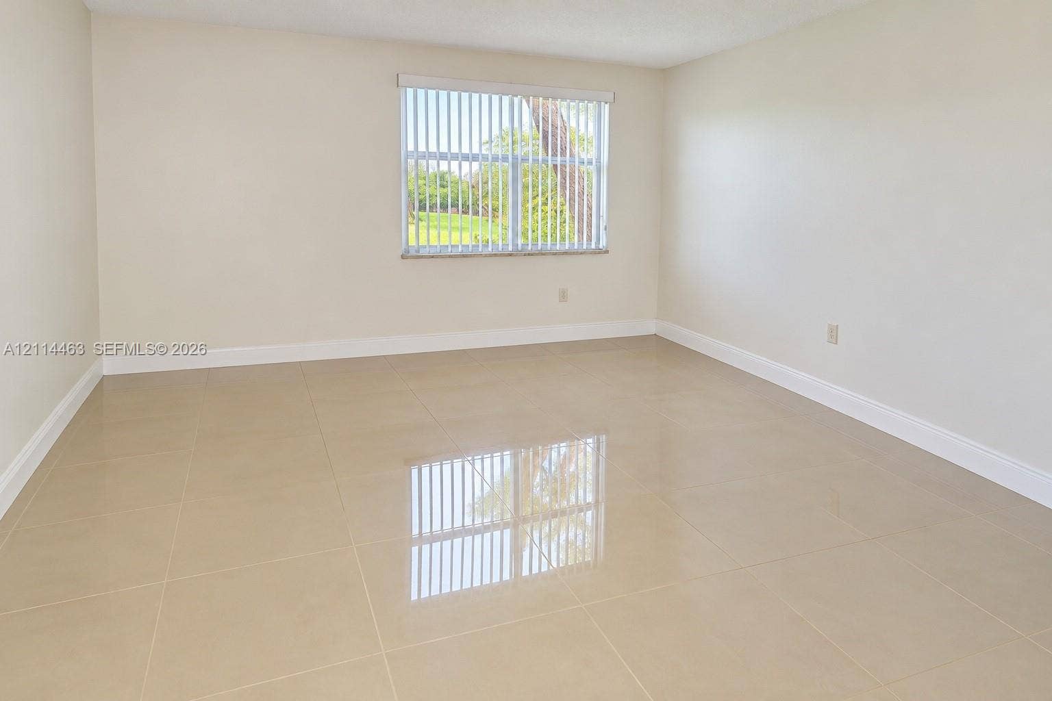 4970 NW 97th Place, #309, Doral, Doral, FL 33178 Neutral-toned interior space featuring polished large-format tile flooring, smooth wall finishes, and a single window with vertical blinds