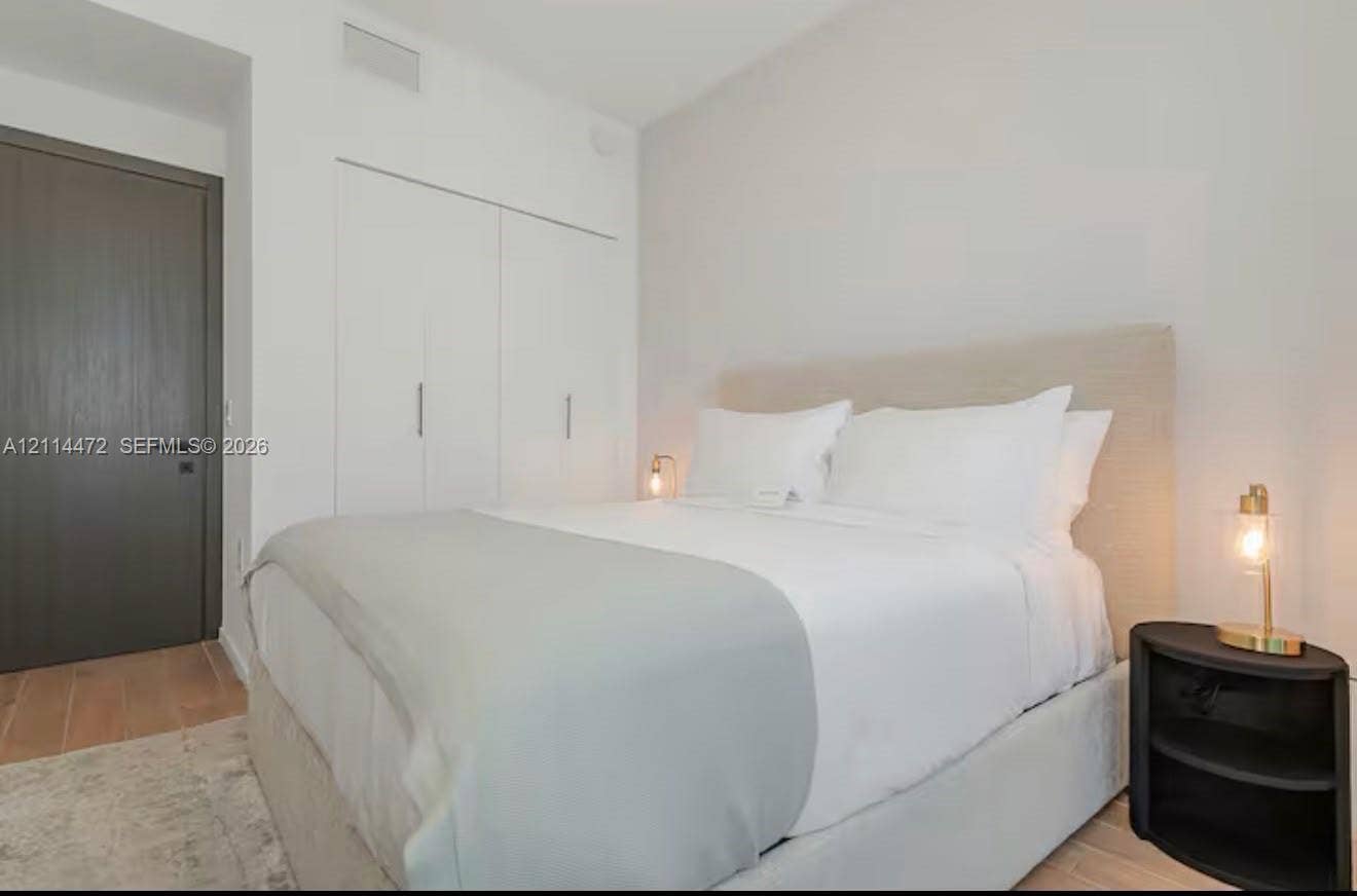 398 NE 5th Street, #4001, Miami, FL 33132 Wood-finish flooring, neutral walls, integrated full-height storage cabinetry with metallic hardware, and a solid-core charcoal interior door