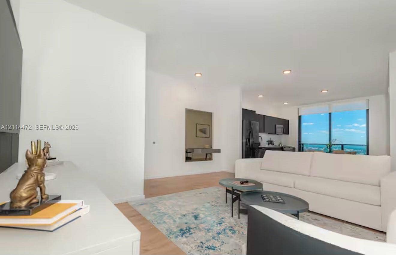 398 NE 5th Street, #4001, Miami, FL 33132 Open-concept interior featuring light wood-finish flooring, recessed lighting, and floor-to-ceiling windows with a distant skyline horizon