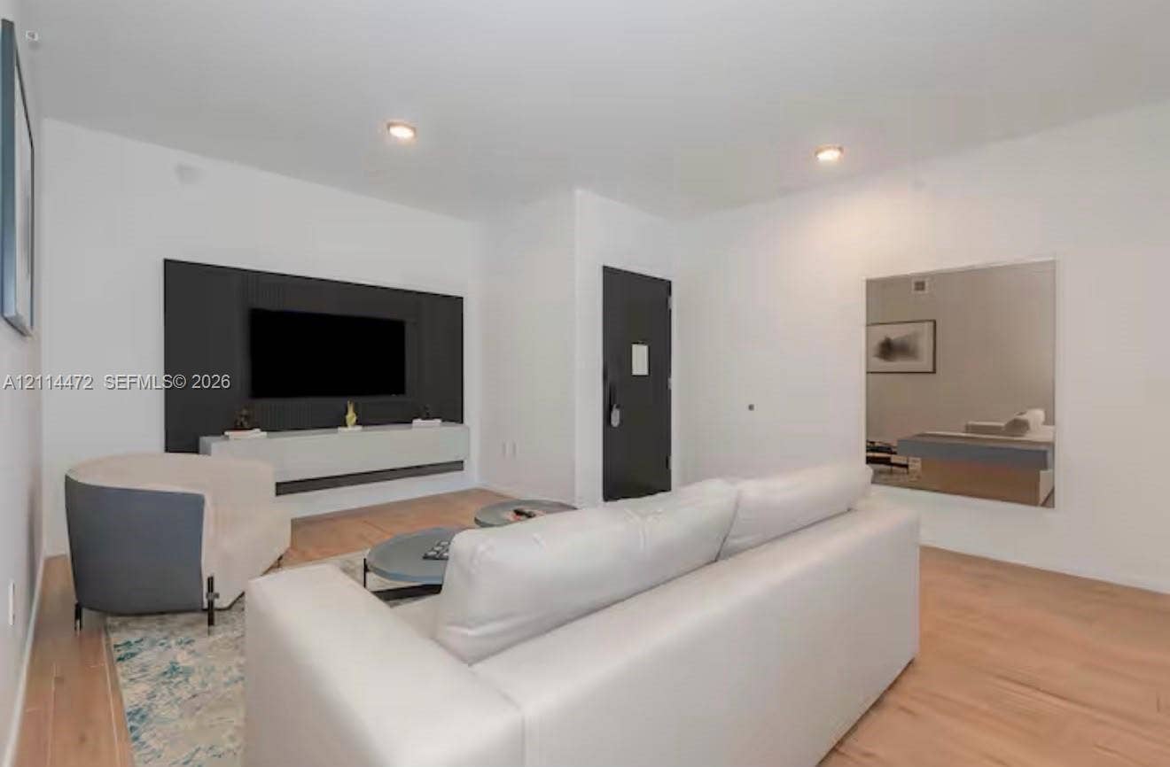 398 NE 5th Street, #4001, Miami, FL 33132 Wood-finish flooring, matte black entry door, wall-mounted floating media console, and recessed lighting