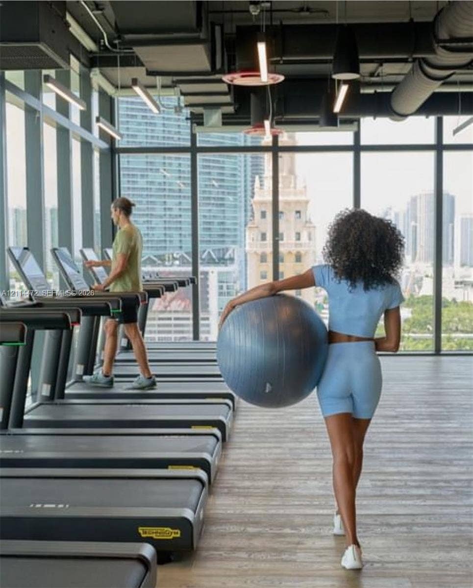 398 NE 5th Street, #4001, Miami, FL 33132 Fitness center featuring floor-to-ceiling windows, wood-finish flooring, exposed industrial-style ceiling, and linear LED lighting