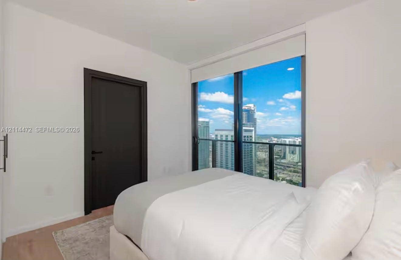 398 NE 5th Street, #4001, Miami, FL 33132 Floor-to-ceiling windows with expansive urban cityscape scenery, dark-finish interior door, recessed lighting, and light-tone wood-finish flooring