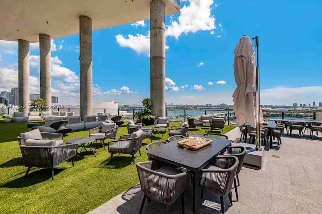 398 NE 5th Street, #4001, Miami, FL 33132 Expansive rooftop terrace featuring synthetic turf flooring, stone tile decking, structural concrete columns, and a glass panel perimeter railing