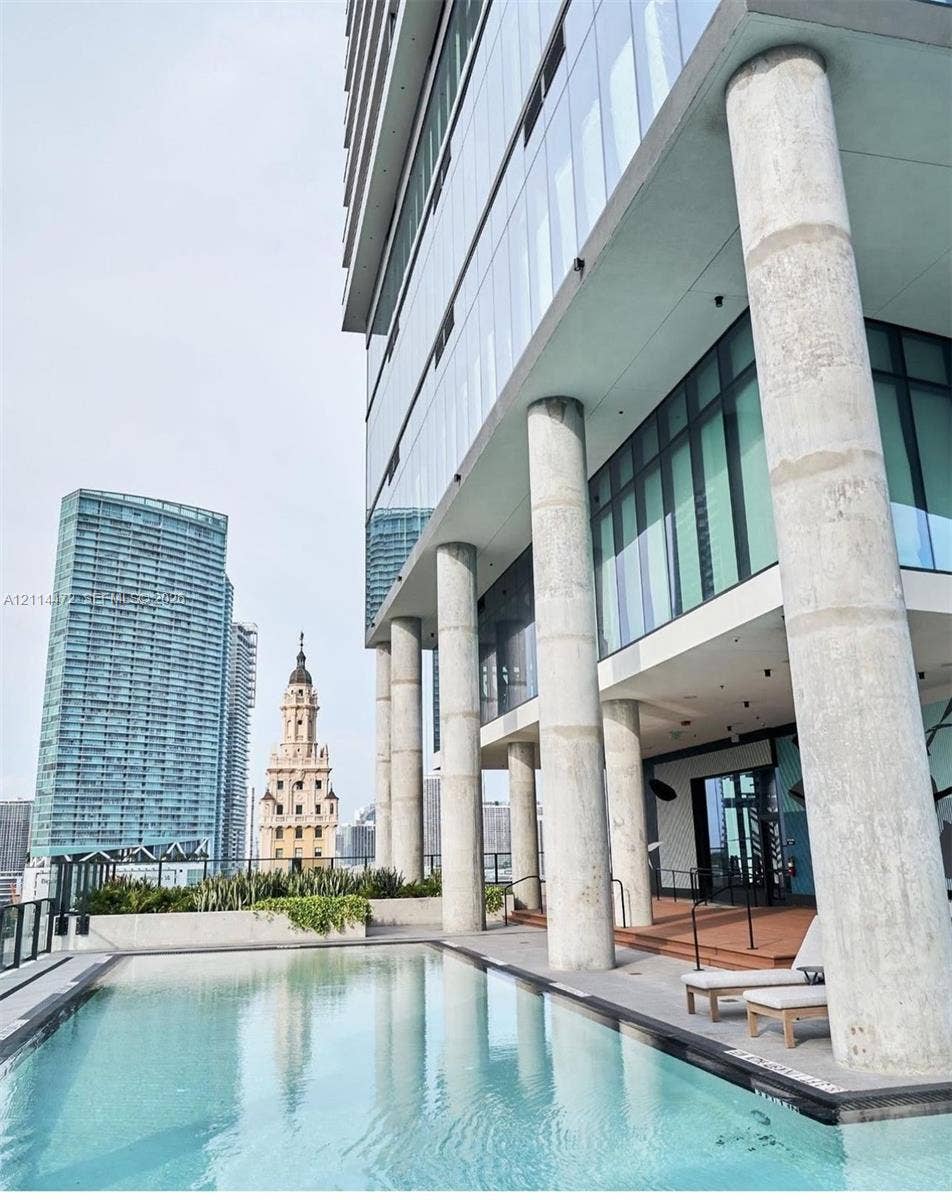 398 NE 5th Street, #4001, Miami, FL 33132 Outdoor swimming pool featuring a concrete deck, floor-to-ceiling glass building facade, and prominent structural columns