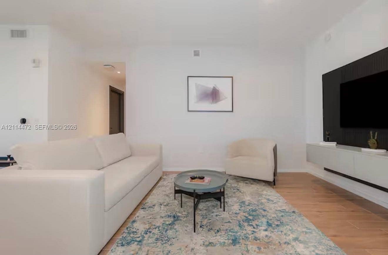 398 NE 5th Street, #4001, Miami, FL 33132 Living space featuring wood-finish flooring, a matte black paneled feature wall, and a wall-mounted floating media console