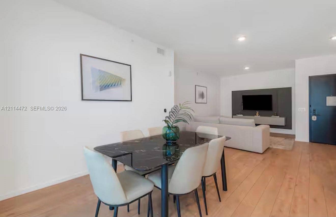 398 NE 5th Street, #4001, Miami, FL 33132 Open-concept interior featuring wood-finish flooring, recessed lighting, and a dark accent wall with a wall-mounted media console