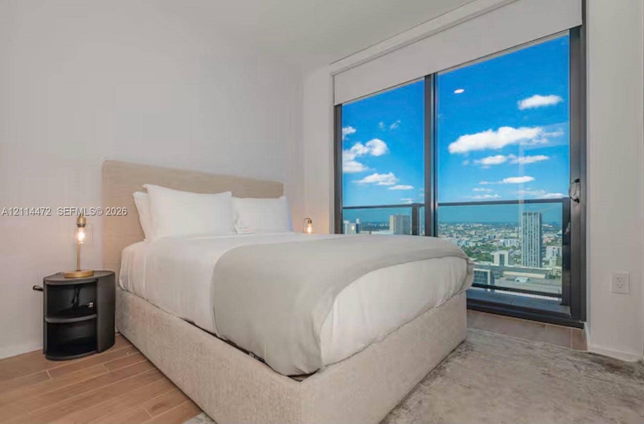 398 NE 5th Street, #4001, Miami, FL 33132 Floor-to-ceiling glass sliding door, metal-frame balcony railing, wood-finish flooring, and recessed ceiling lighting