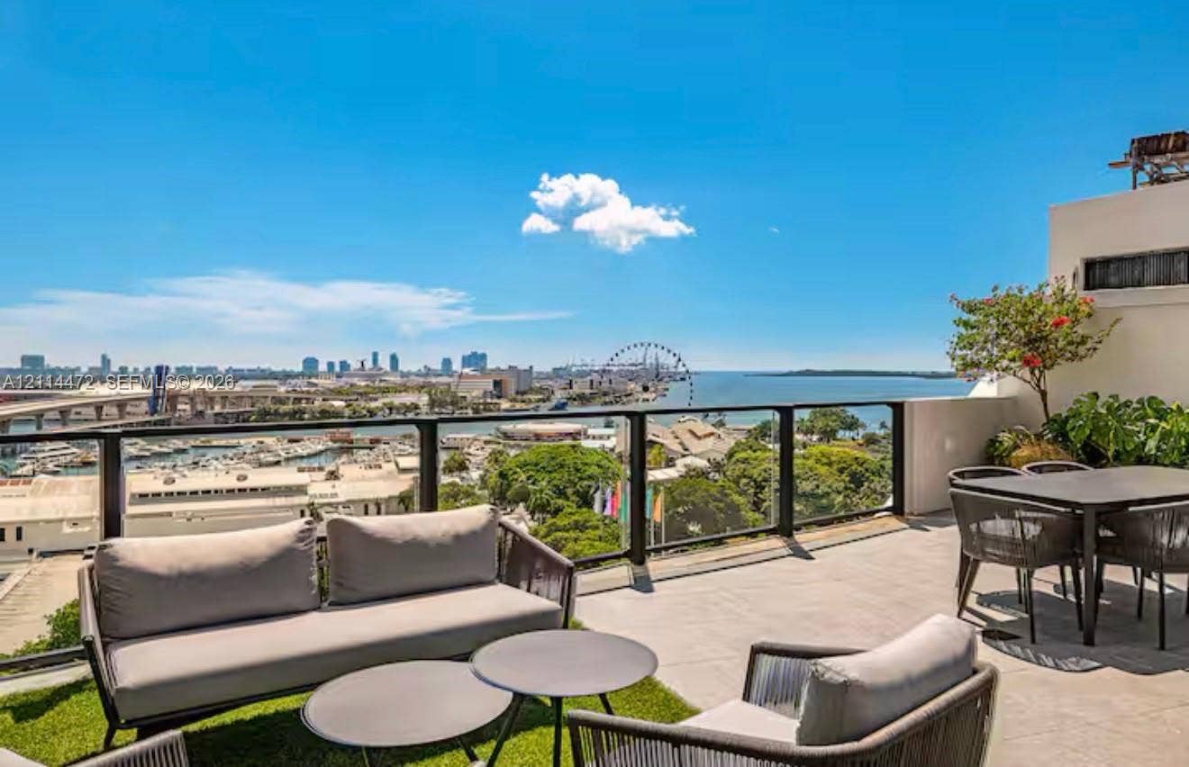 398 NE 5th Street, #4001, Miami, FL 33132 Elevated terrace with large-format tile flooring, perimeter glass railing, and panoramic water and city skyline backdrop