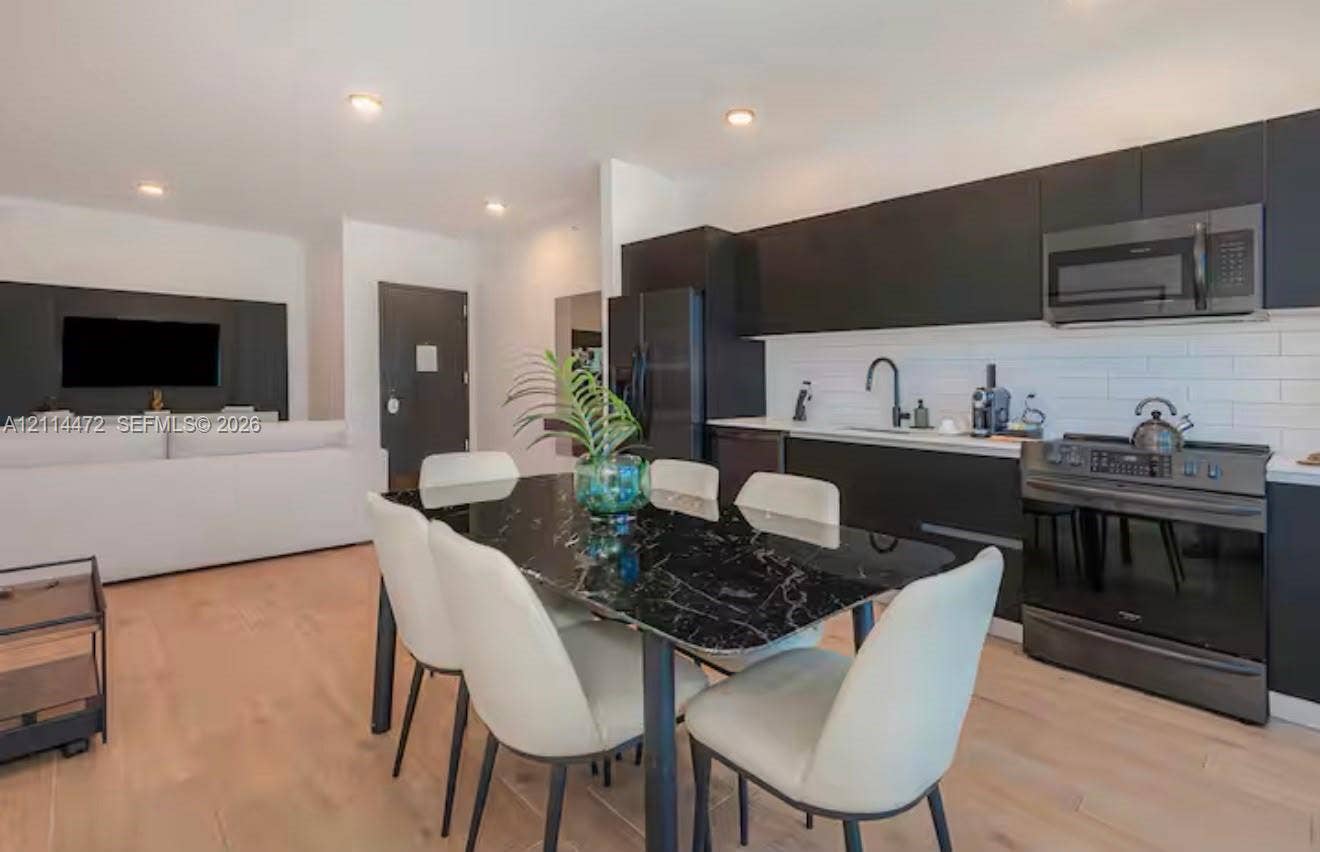 398 NE 5th Street, #4001, Miami, FL 33132 Kitchen featuring matte black flat-panel cabinetry, white subway tile backsplash, light-toned wood-finish flooring, and recessed ceiling lighting