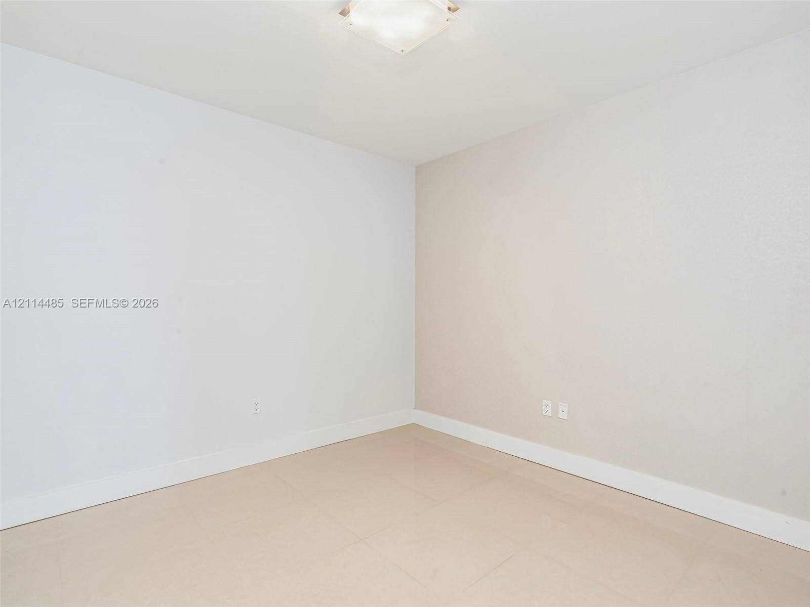 Neutral interior space featuring polished tile flooring, light-toned walls, and a square ceiling-mounted light fixture