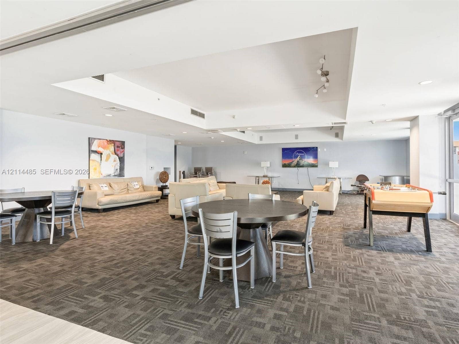 Open-concept common area featuring recessed ceiling details, neutral carpeting, and track lighting