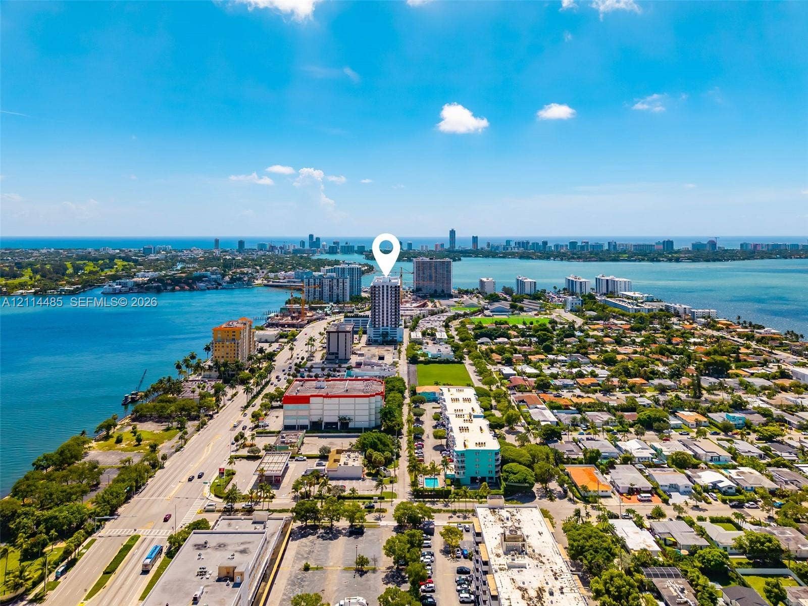 Aerial perspective featuring a high-rise structure situated on a coastal peninsula with direct water frontage and proximity to surrounding urban infrastructure