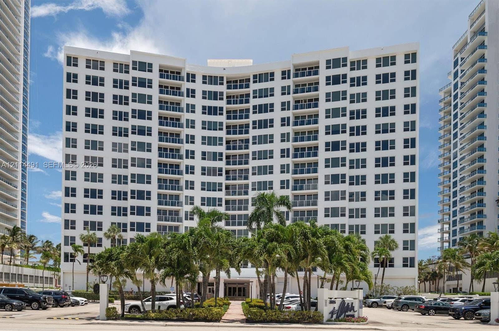 3505 S Ocean Drive, #217, Hollywood, FL 33019 High-rise residential exterior featuring white stucco facade, symmetrical balcony configuration, expansive glass windows, and landscaped grounds with mature palm trees