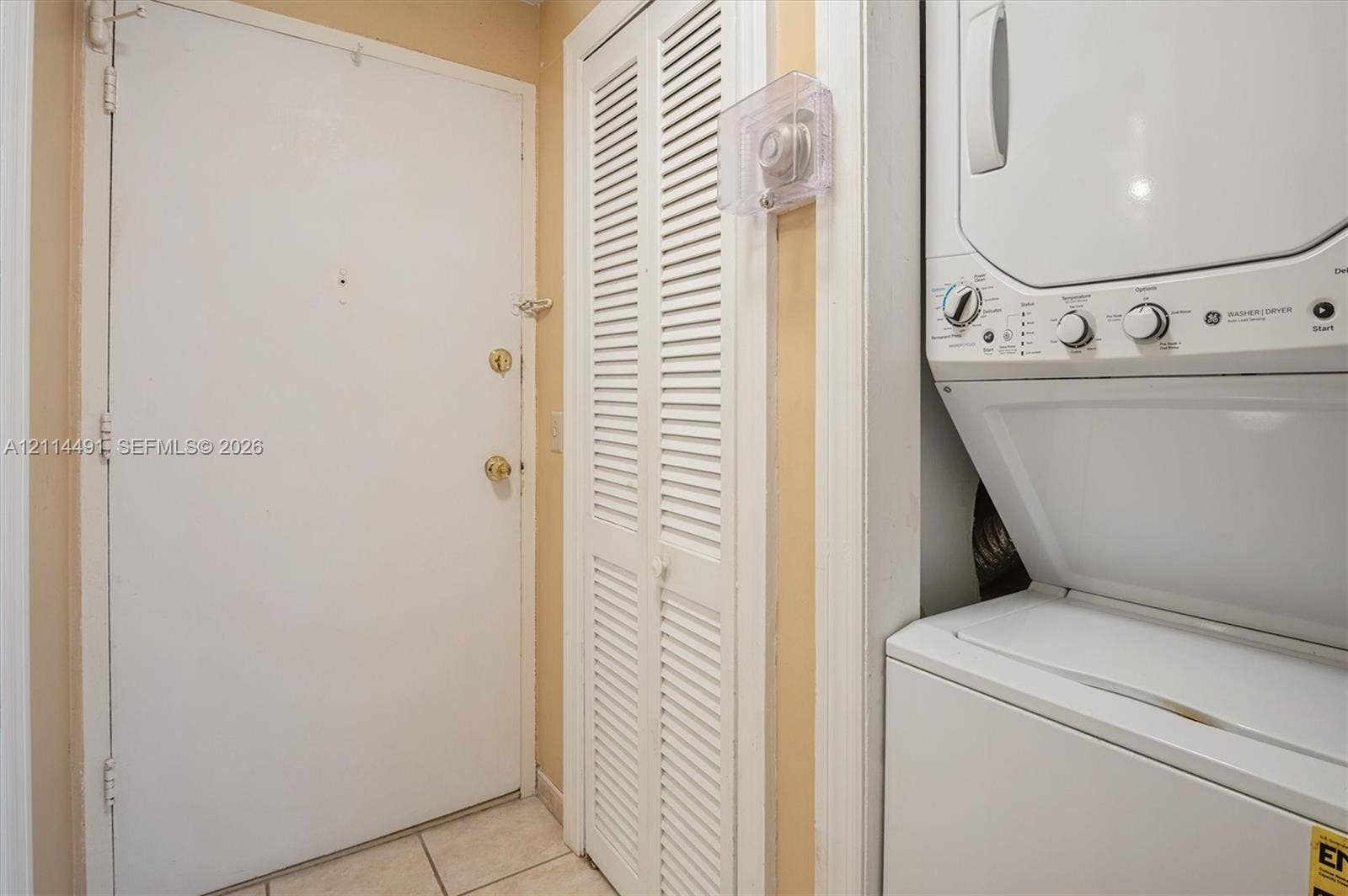 3505 S Ocean Drive, #217, Hollywood, FL 33019 Laundry area featuring a stackable washer and dryer unit, louvered closet doors, and tile flooring